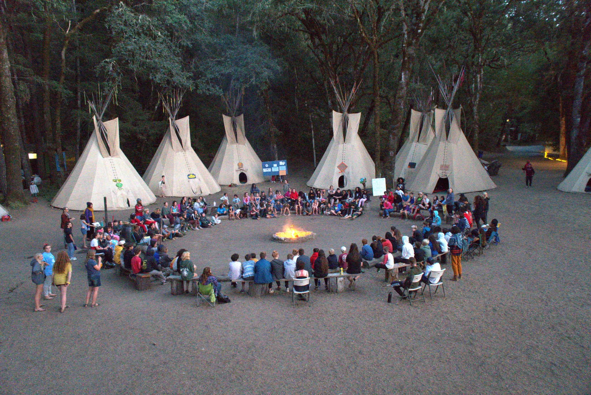 Wide view of people gathered around a fire circle at camp