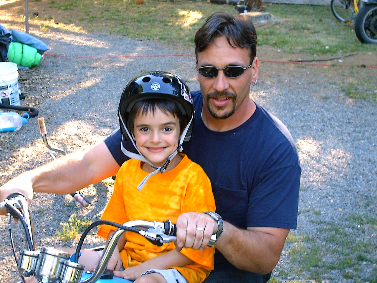 Micah Owens sitting on a motorcycle with a child wearing a helmet