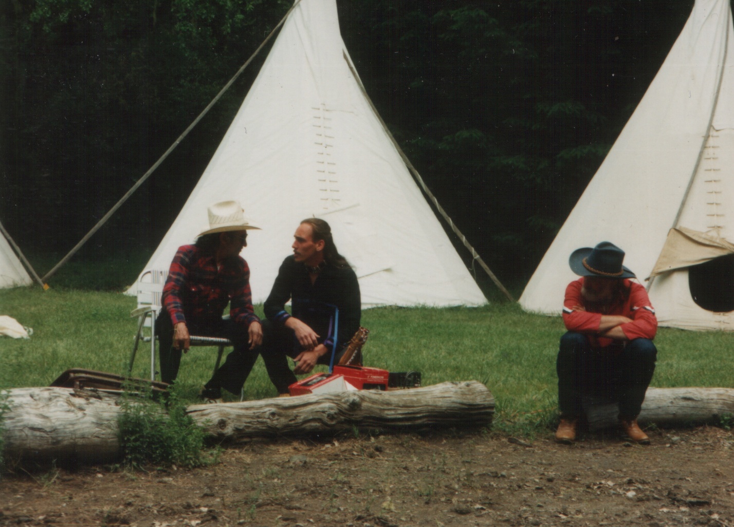 Older camp photograph with people sitting near tipis